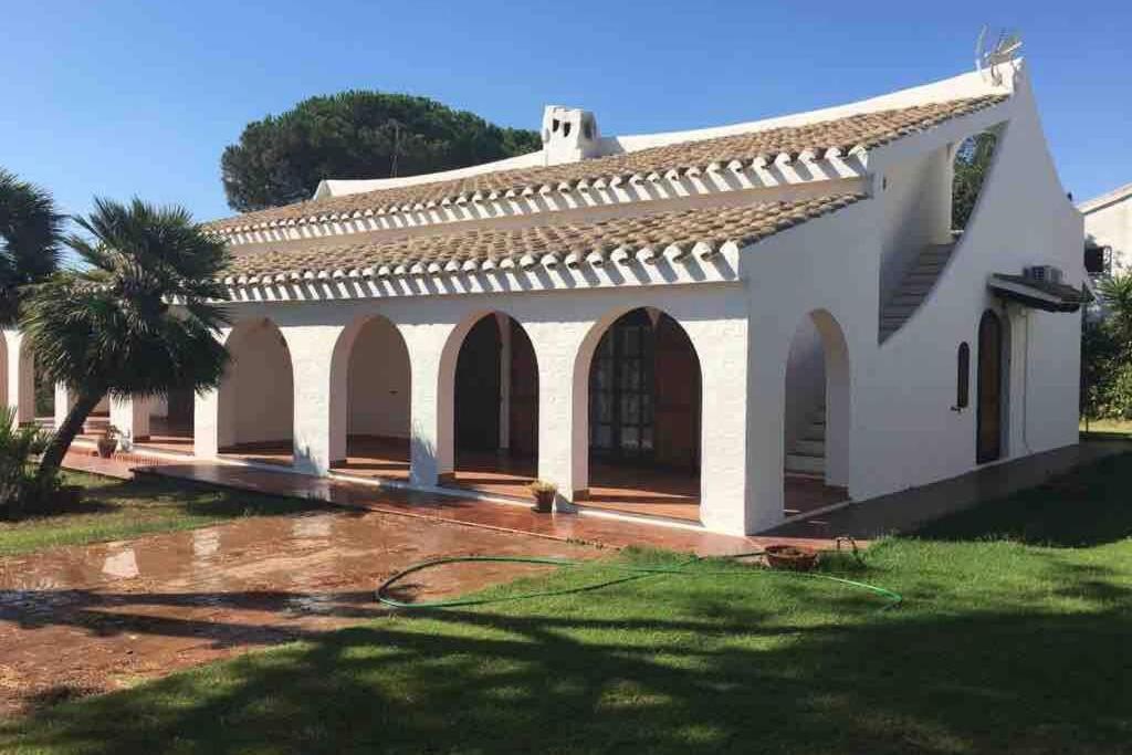 uma grande casa branca com arcos e uma palmeira em Villa Spiga & Serena em Porto Columbu - Perdʼe Sali