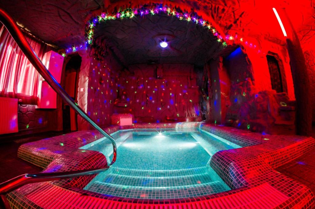 bañera de hidromasaje en una habitación con luces rojas en Eden Garden Sovata en Sovata