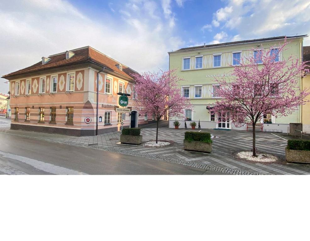 a building with pink trees in front of a street at Gasthof Hametner mit Innviertlerhof mit direktem Zugang zur Therme Mediterrana durch unseren Garten! in Bad Hall