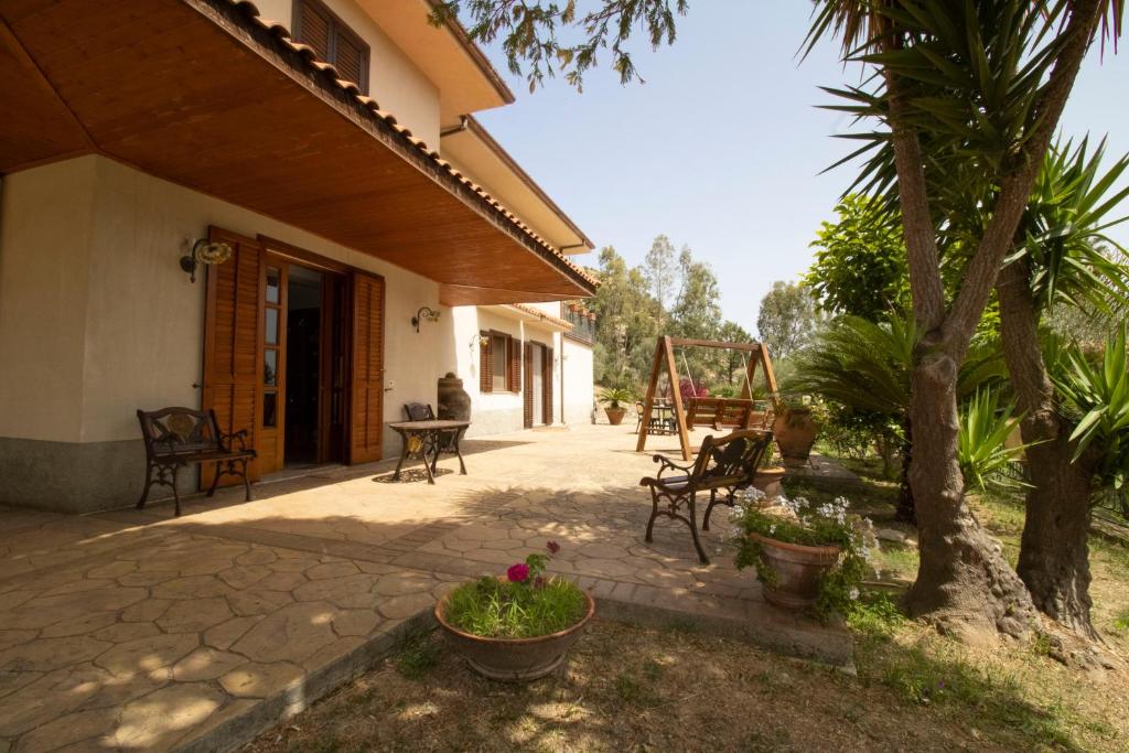 un patio di una casa con sedie e alberi di Villa privata con ingresso gratuito al beach club, Villa Mingari a Santo Stefano di Camastra