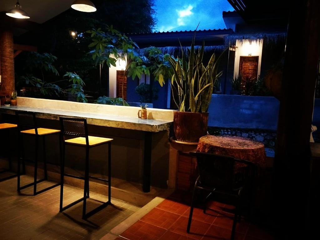 a bar with chairs and a counter at night at Cheeva at pai ชีวา แอท ปาย in Pai