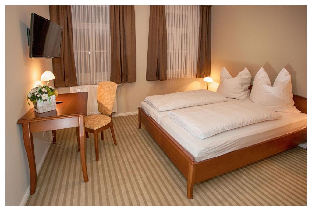 ein Hotelzimmer mit einem Bett, einem Schreibtisch und einem TV in der Unterkunft Postillion in Velpke