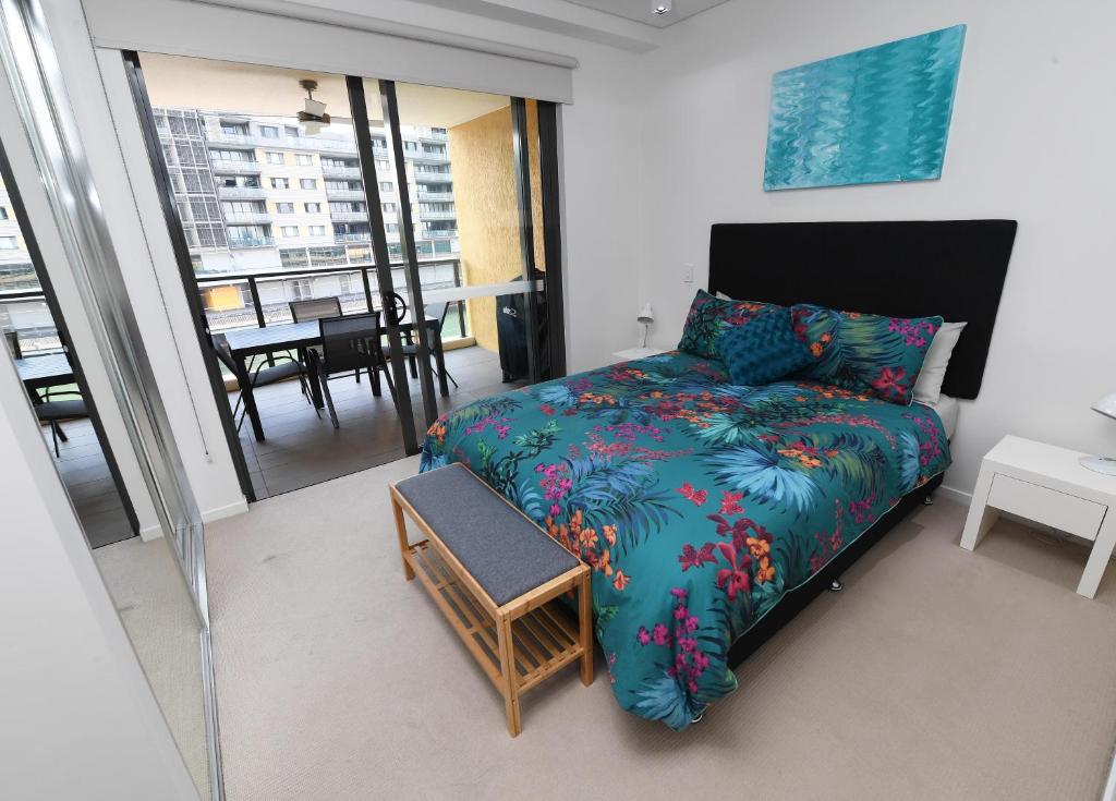 a bedroom with a bed and a balcony with a table at WATERFRONT DARWIN TROPICAL GEM in Darwin