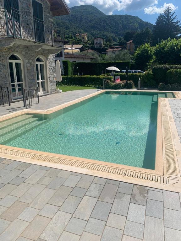 a swimming pool with blue water in front of a house at BellaGiò Apartment pool free parking near lake in Bellagio