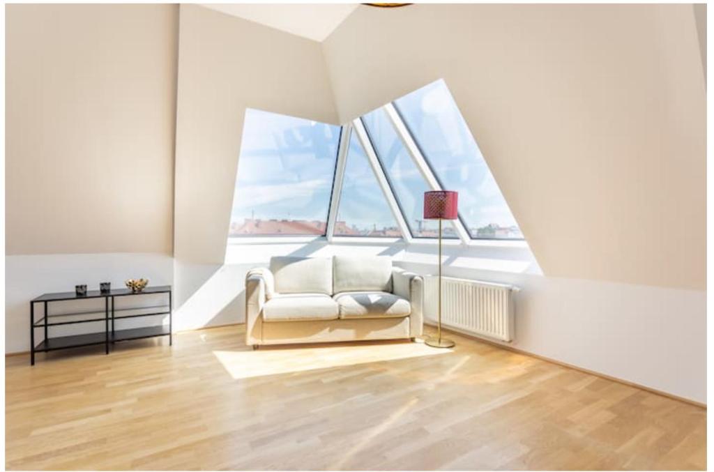 ein Wohnzimmer mit einem weißen Stuhl und großen Fenstern in der Unterkunft N45 · Penthouse near Schoenbrunn. Amazing Terrasse! N45 in Wien