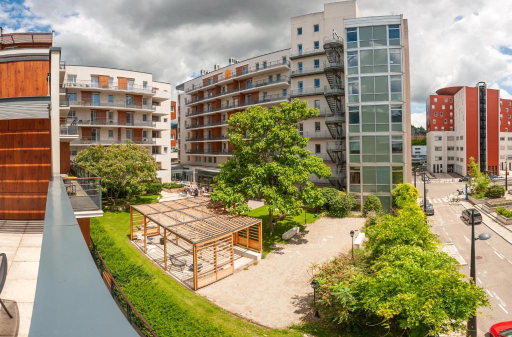 a park in the middle of a city with buildings at Apparthotel Le Hüb Grenoble in Grenoble