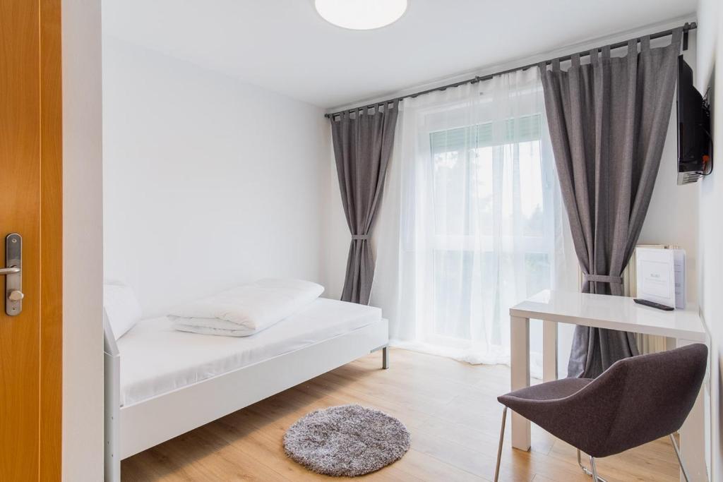 um pequeno quarto com uma cama e uma janela em Appartement Graz - Ihr erstklassiges Zuhause fernab von Zuhause em Graz