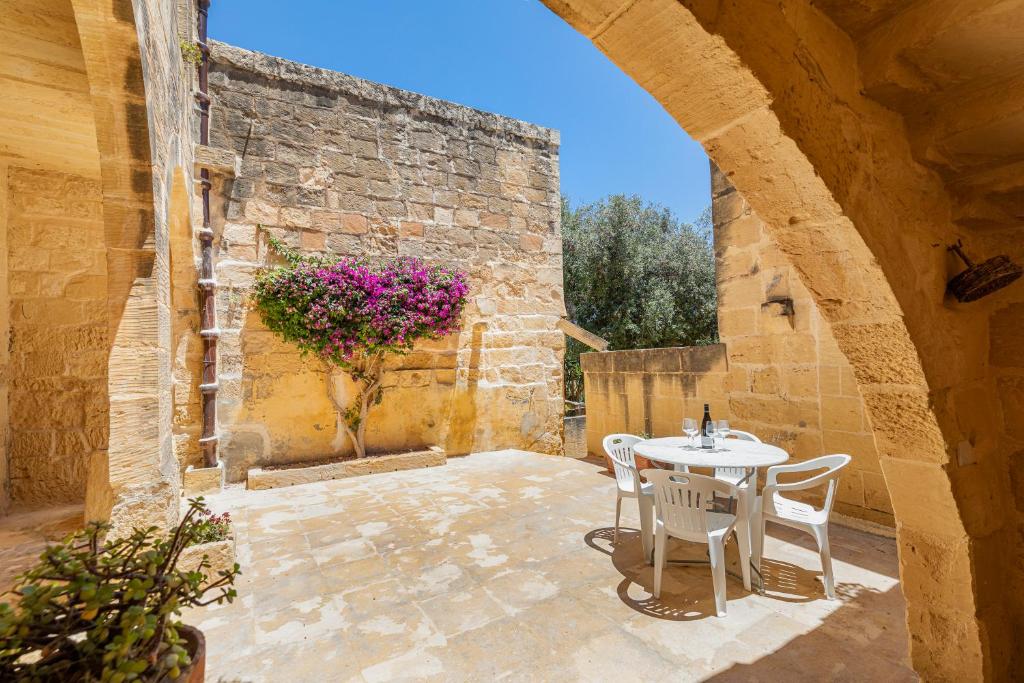 an outdoor patio with a white table and chairs at Razzett Ghasri in Għasri