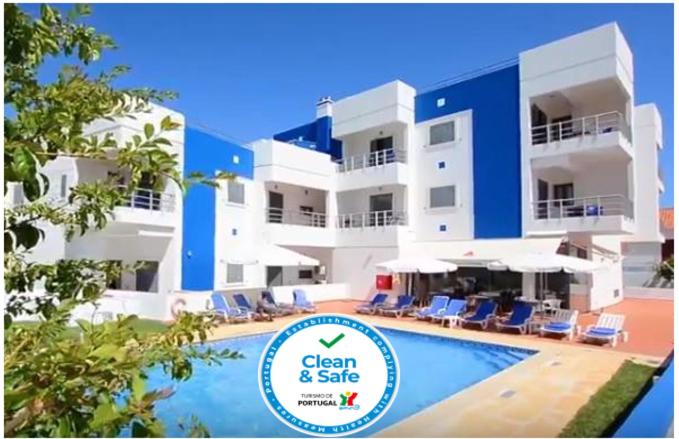 a large building with a pool and chairs and a sign at Vicentina Hotel in Aljezur