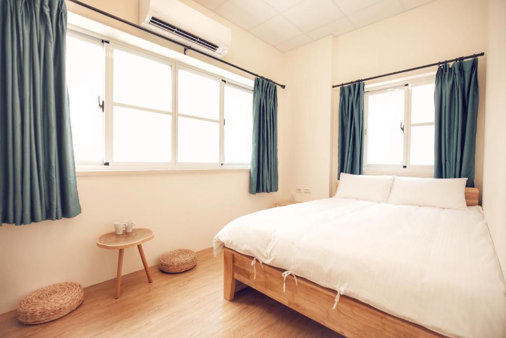 a bedroom with a bed and two windows at Yua Ya B&B in Tainan