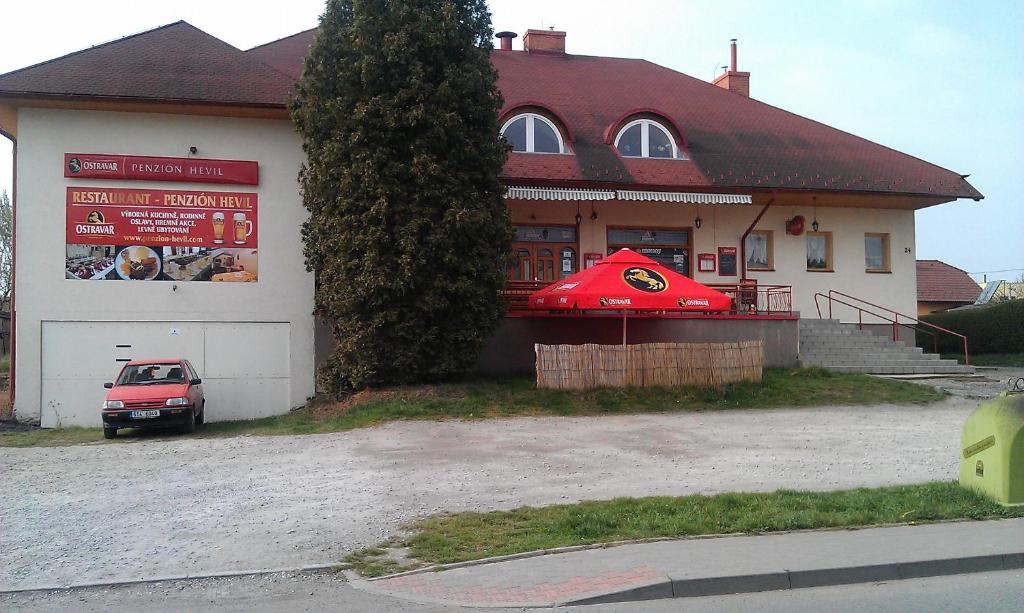 un bâtiment avec une voiture garée devant lui dans l'établissement Restaurant-Penzión HEVIL, à Hlučín