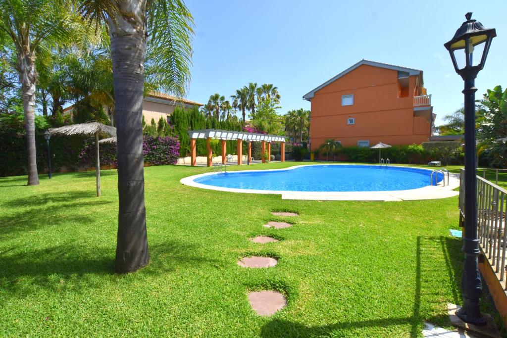 a yard with a swimming pool and a palm tree at Apartamento Nueva Fontana in Jávea