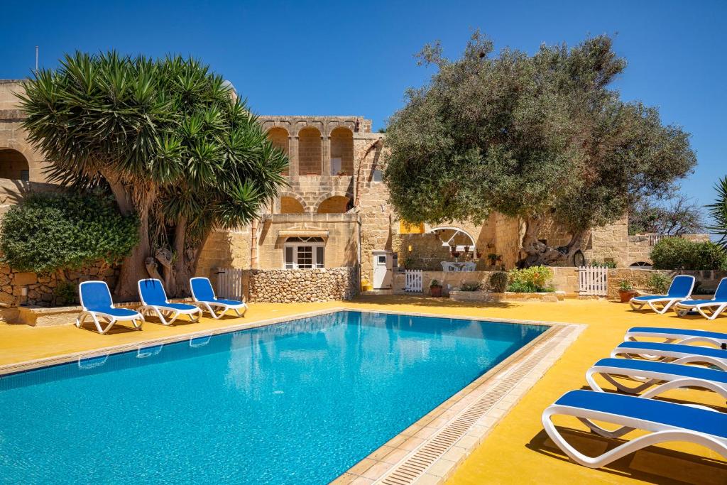 a swimming pool with lounge chairs and a house at Razzett Ghasri in Għasri