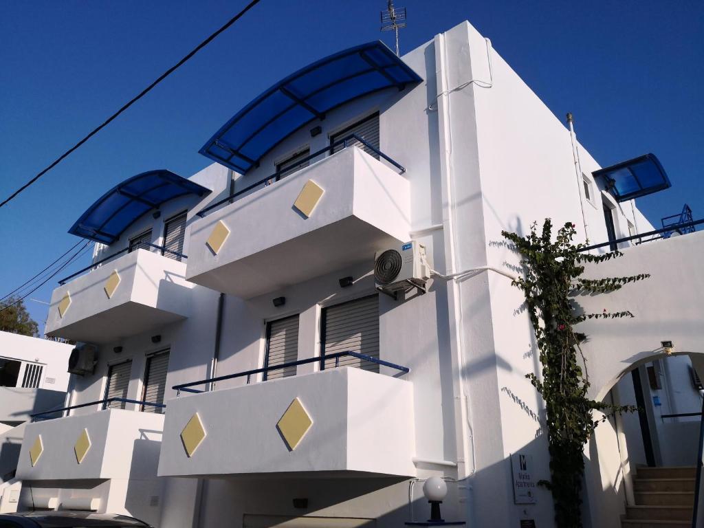 - un bâtiment blanc avec des balcons bleus et jaunes dans l'établissement Marika Apartments, à Mastichari