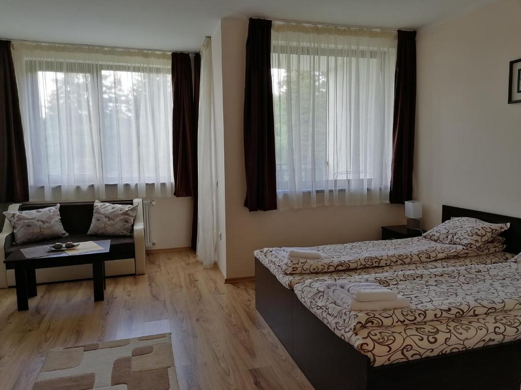 a bedroom with two beds and a couch and windows at Borovets Gardens Studio D36 in Borovets