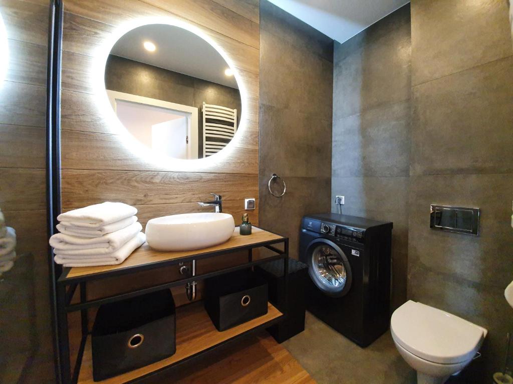 a bathroom with a sink and a washing machine at Apartamenty Azure - 365PAM in Kołobrzeg