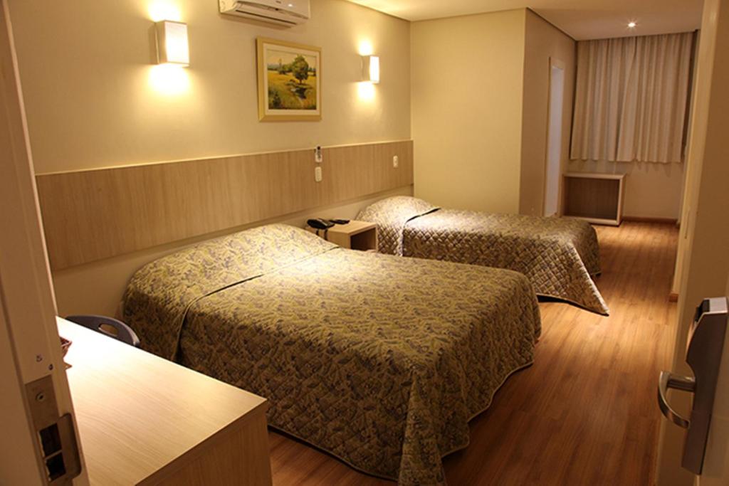 a hotel room with two beds and a television at Golden Hotel in Chapecó