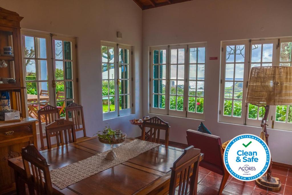 a dining room with a table and chairs and windows at Quinta das Bolas in Ponta Delgada