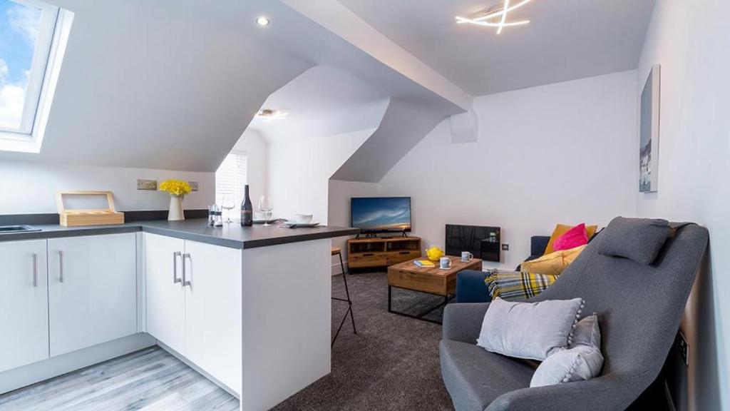 a kitchen and living room with white cabinets and a couch at Station Loft in Deganwy