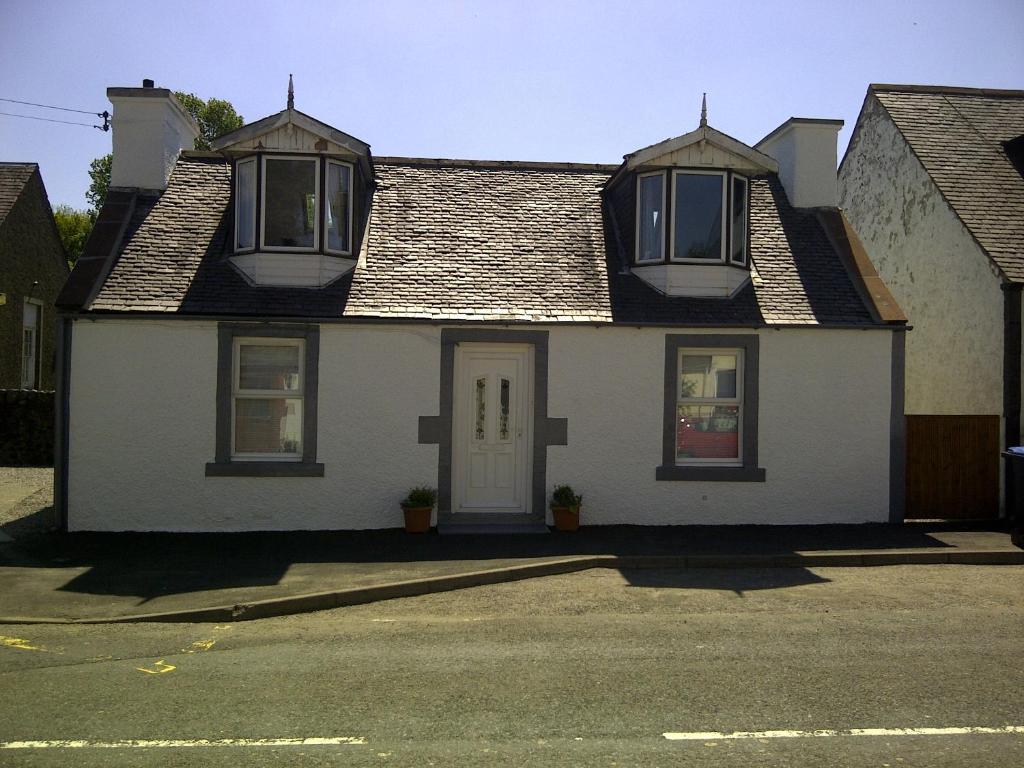 Biały dom z dwoma oknami i drzwiami w obiekcie RoSE COTTAGE THREE BEDROOM HOUSE WITH PARKING w mieście Carsphairn