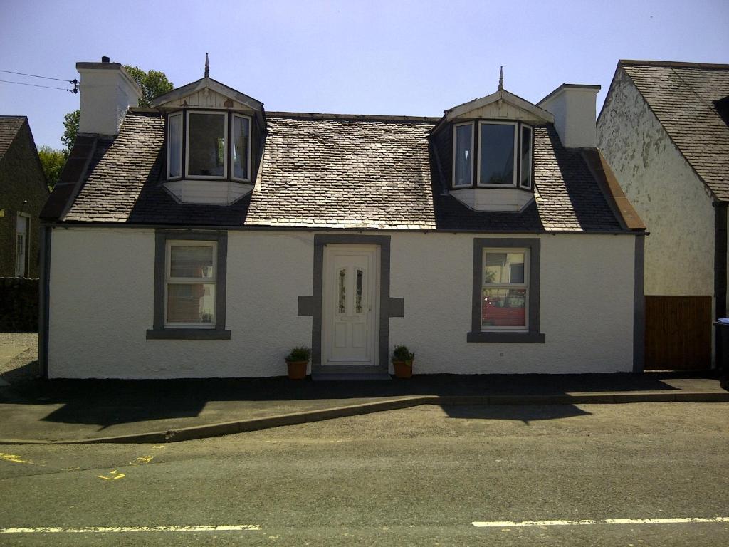 a white house with two windows and a door at RoSE COTTAGE THREE BEDROOM HOUSE WITH PARKING Spring Special in Carsphairn