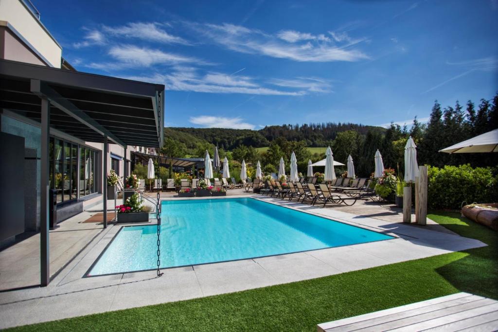 einen Pool in einem Resort mit Stühlen und Sonnenschirmen in der Unterkunft Göbels Schlosshotel "Prinz von Hessen" in Friedewald