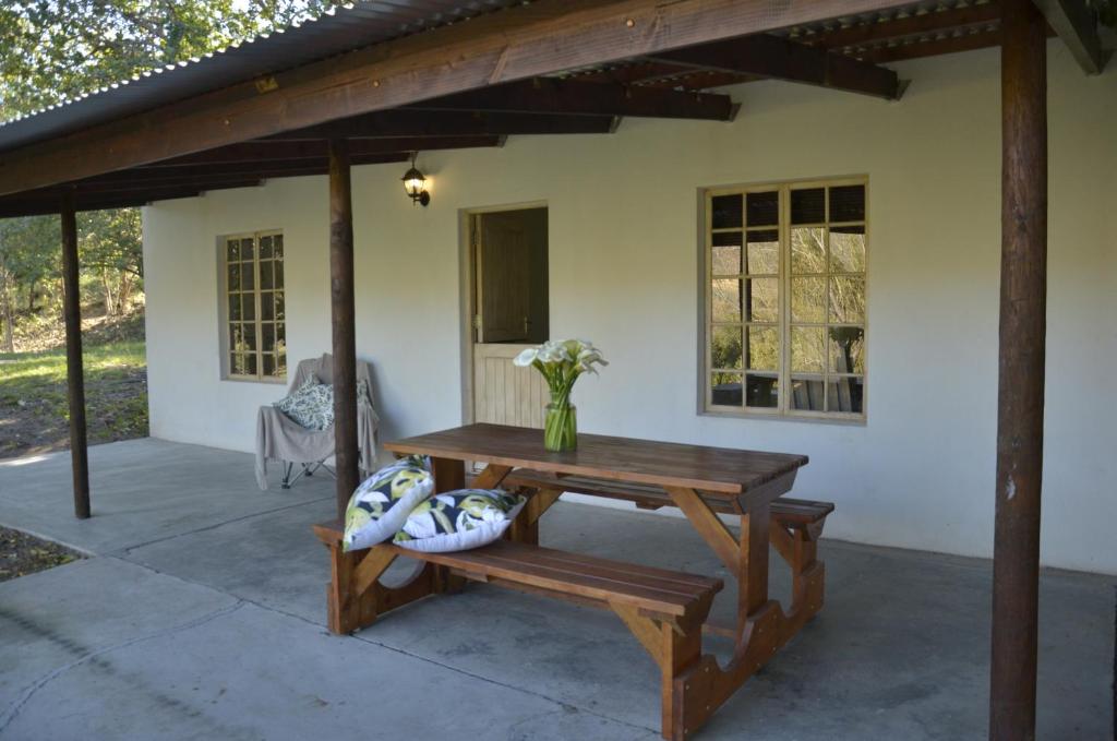 a patio with a wooden table and a bench at Boskloof Swemgat in Clanwilliam