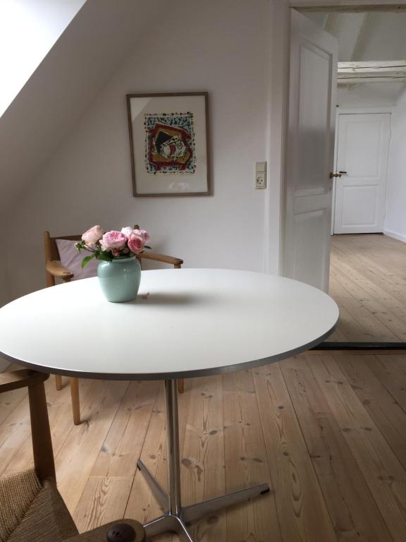 a white table with a vase of flowers on it at Birgittes B&B i Jelling in Jelling