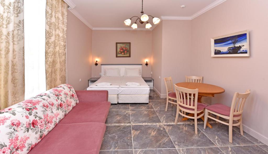 a living room with a bed and a table at Sirena Palace Family Hotel in Obzor