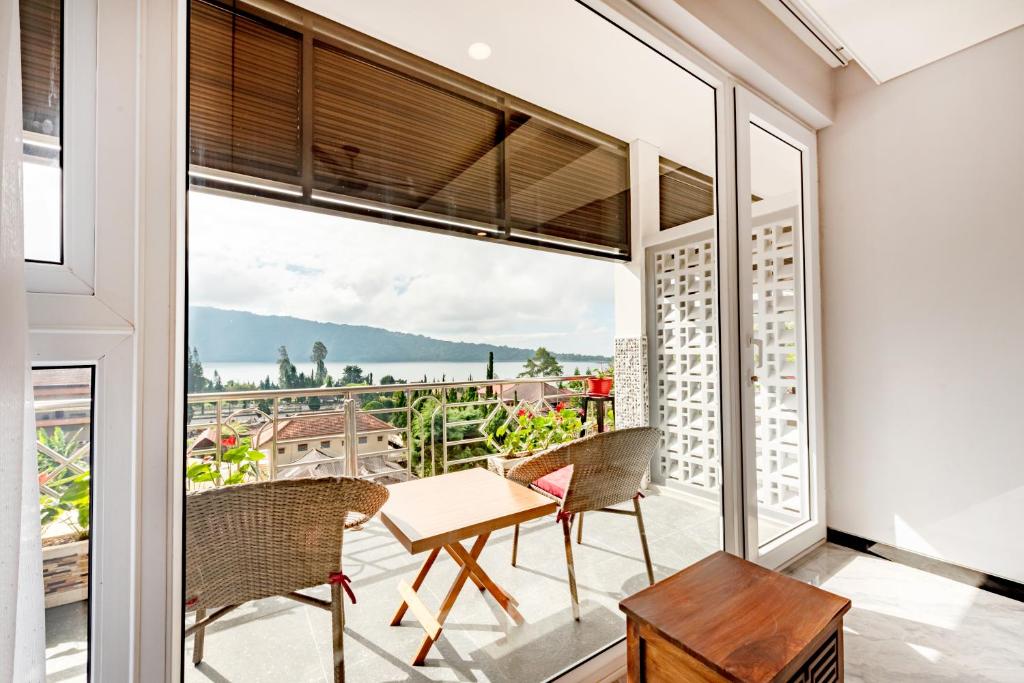 a room with a balcony with a table and chairs at Dedanau Hotel in Bedugul