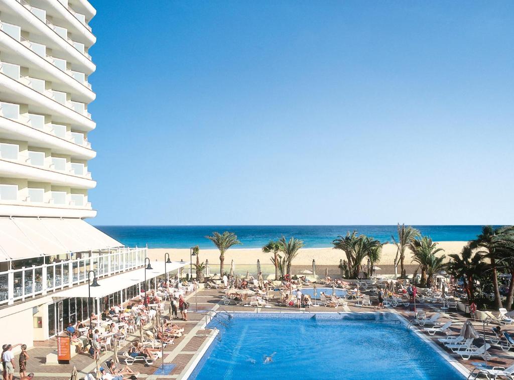 a hotel with a swimming pool next to a beach at Hotel Riu Oliva Beach Resort - All Inclusive in Corralejo
