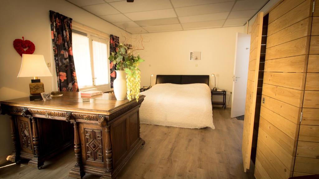 Un dormitorio con una cama y una mesa con un jarrón de flores en Rumah Senang en Den Helder