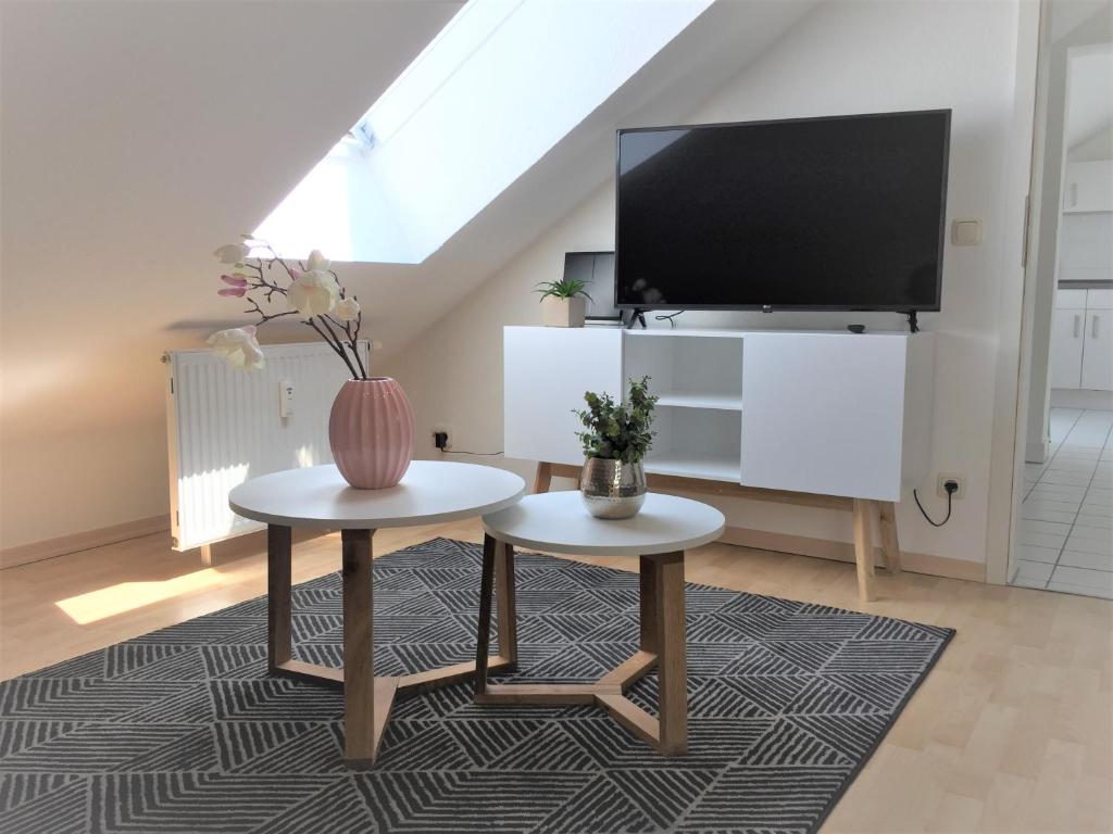 een woonkamer met een tv en 2 tafels bij Zwillingsperlen Leutzsch - Appartement Villenblick in Leipzig