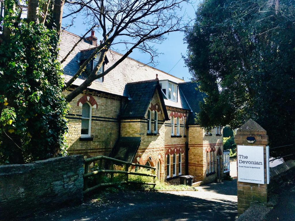 une maison en briques avec un panneau devant elle dans l'établissement The Devonian, à Ilfracombe