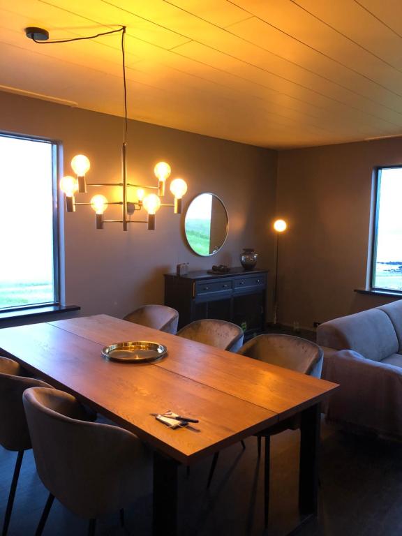 Hellnar Ocean View Villa في هيلنار: غرفة طعام مع طاولة وكراسي خشبية