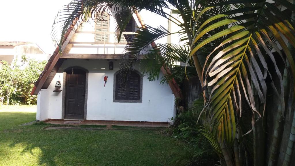 uma casa branca com uma porta preta e uma palmeira em Chalet da vila em Angra dos Reis