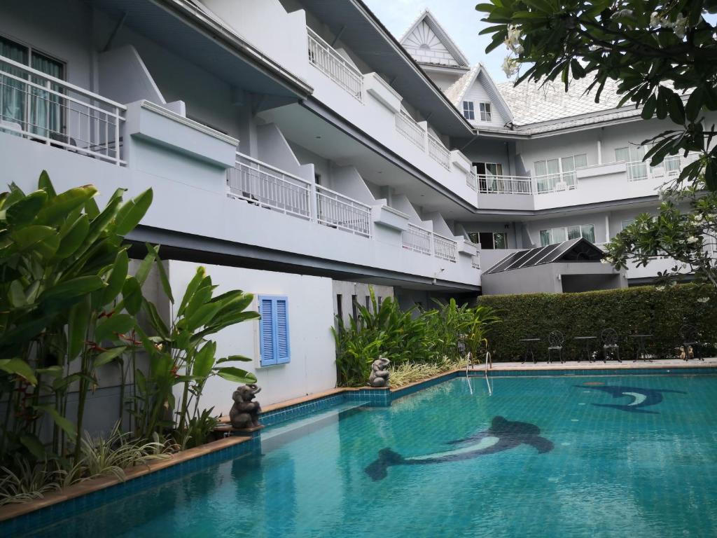 a person swimming in a swimming pool next to a building at Baan Suksiri Hotel in Hua Hin