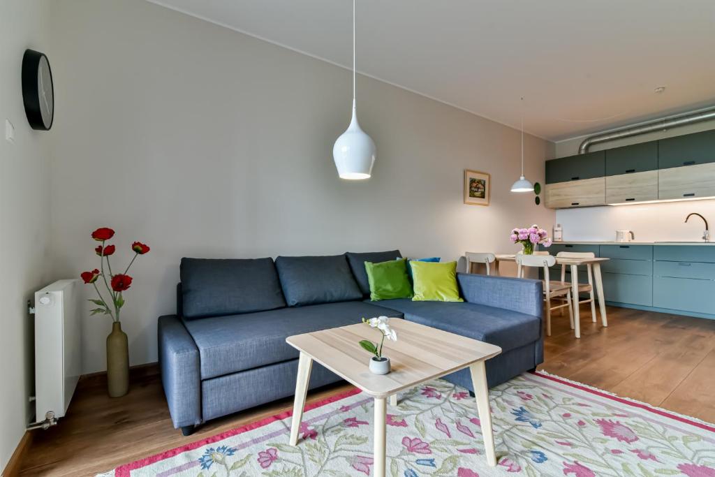 ein Wohnzimmer mit einem blauen Sofa und einem Tisch in der Unterkunft LTC Apartments Silva in Gdynia
