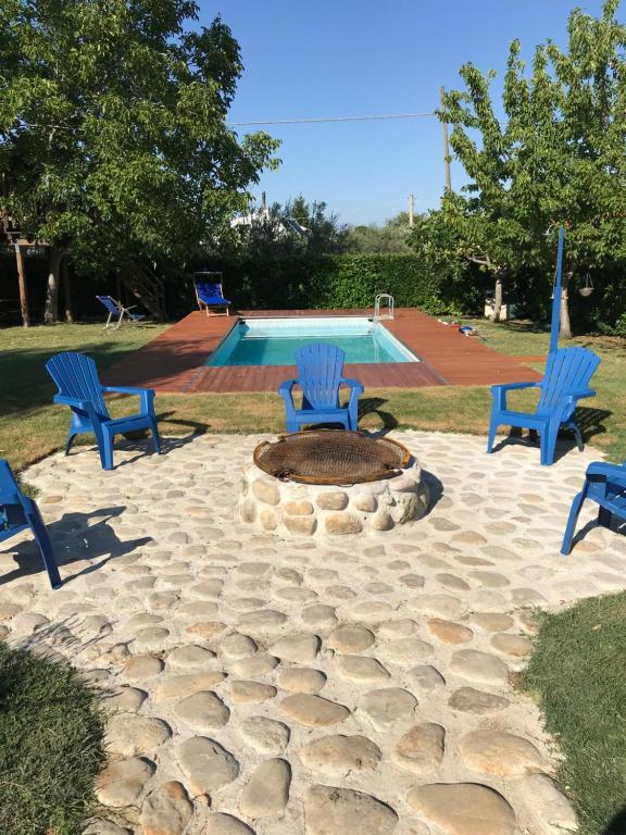 een vuurplaats met drie blauwe stoelen en een zwembad bij Casa Gavenniae in Nocciano