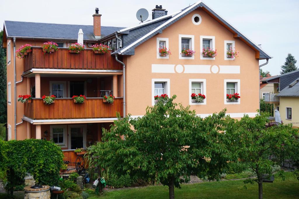 a house with flower boxes on the windows at Ferienwohnung am Dorfplatz in Kurort Gohrisch