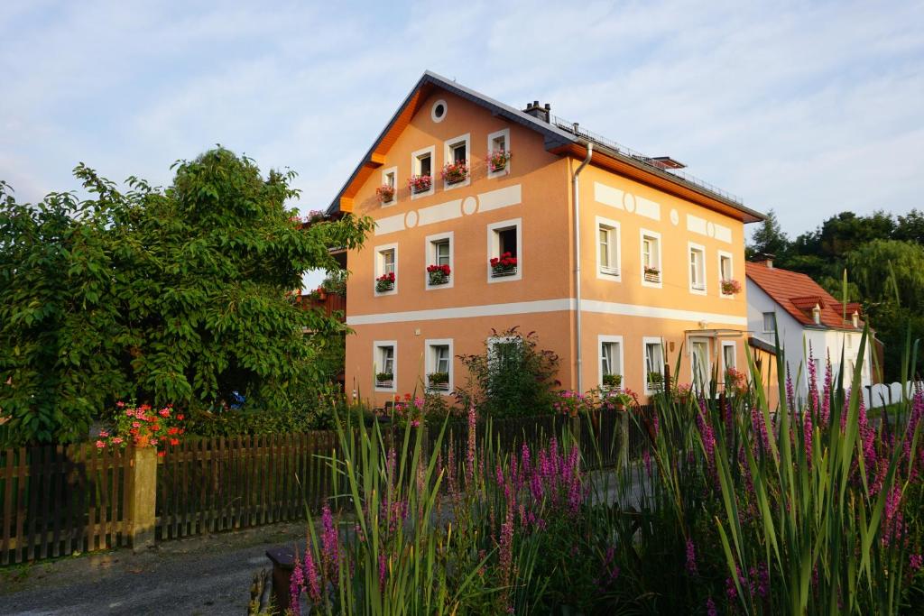 a house with a fence and flowers in front of it at Ferienwohnung am Dorfplatz in Kurort Gohrisch