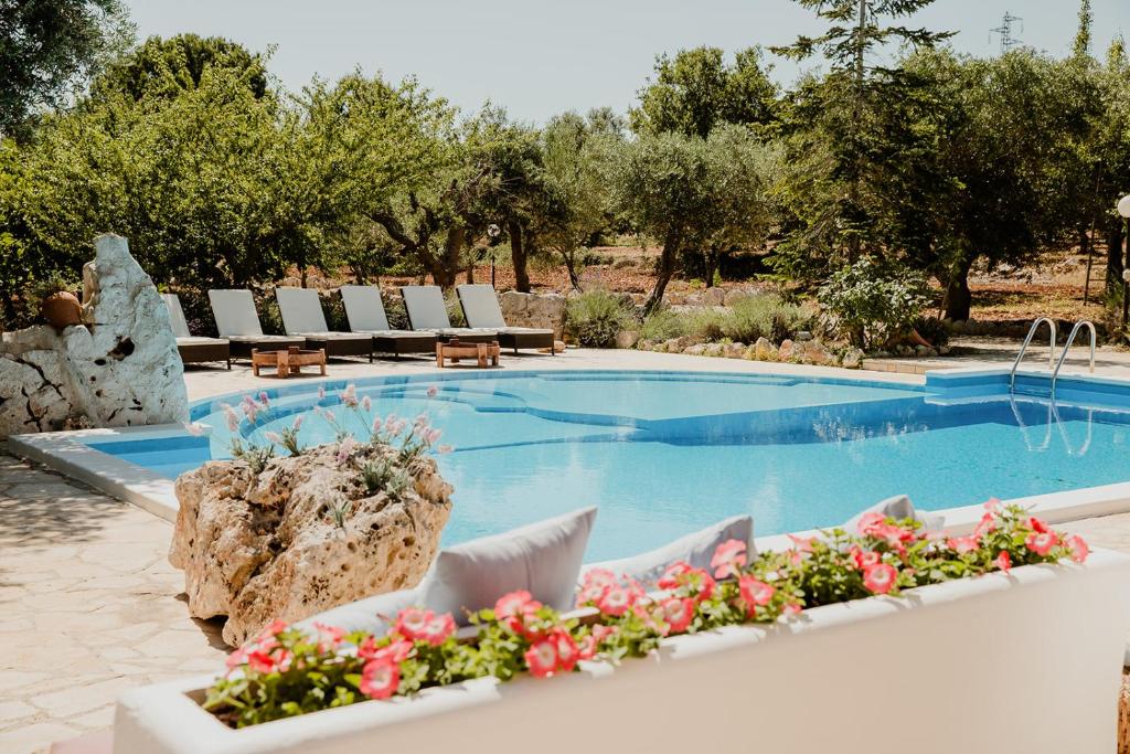 a pool with chairs and flowers in front of it at Antica Tenuta dei Trulli in Alberobello