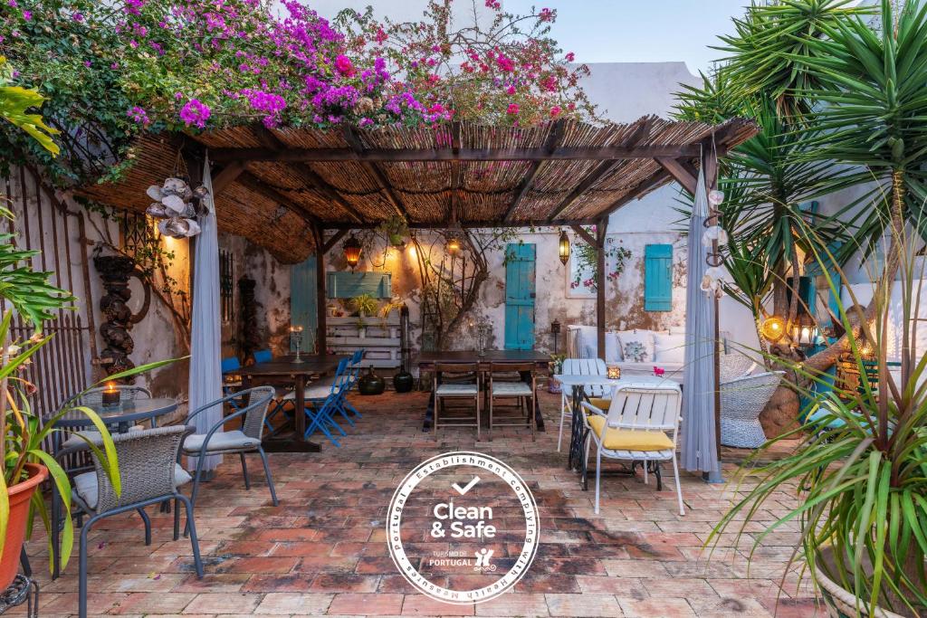 un patio con mesa, sillas y flores en Casa dos Arcos - Charm Guesthouse, en Albufeira
