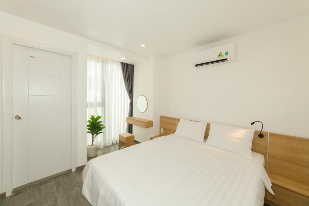 a white bedroom with a white bed and a window at CIEN hotel in Quy Nhon