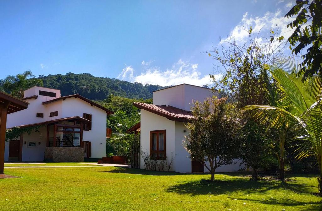 una casa blanca con un patio verde con un árbol en Pousada Asa do Vento en São Luiz do Paraitinga