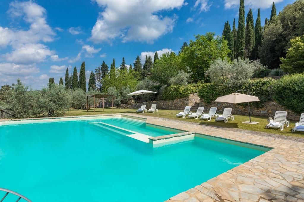 una piscina en un patio trasero con sillas y árboles en Casale Giglio, en Pergine Valdarno