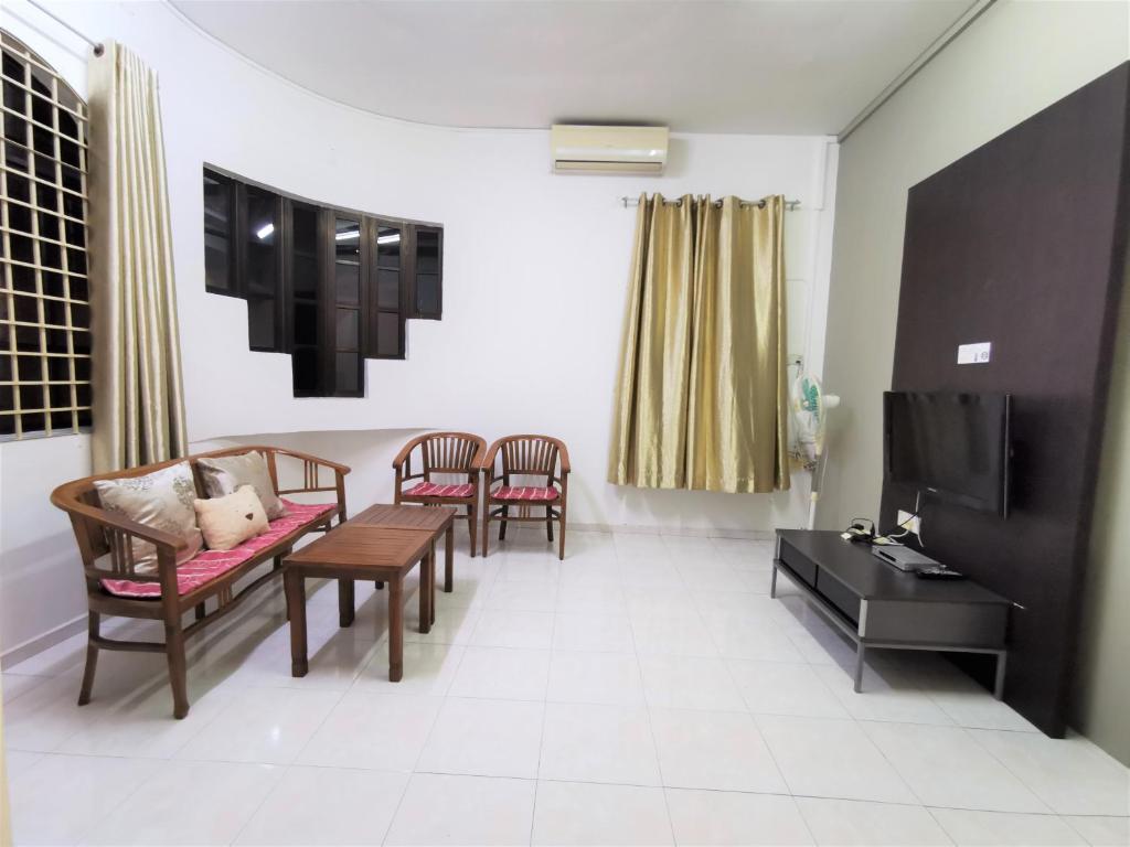 a living room with chairs and a table and a tv at Warni Villa 8 Whole Or Room in Muar