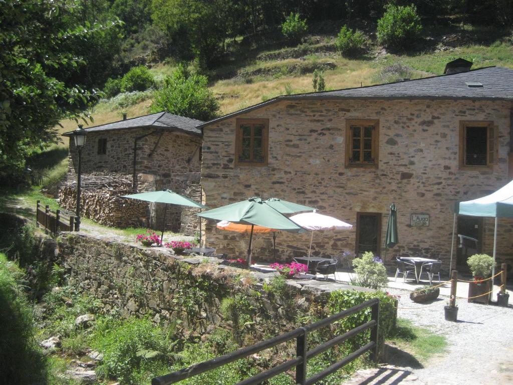 un edificio de piedra con 2 sombrillas y una mesa en Casa da Sapeira en Santa Eulalia de Oscos
