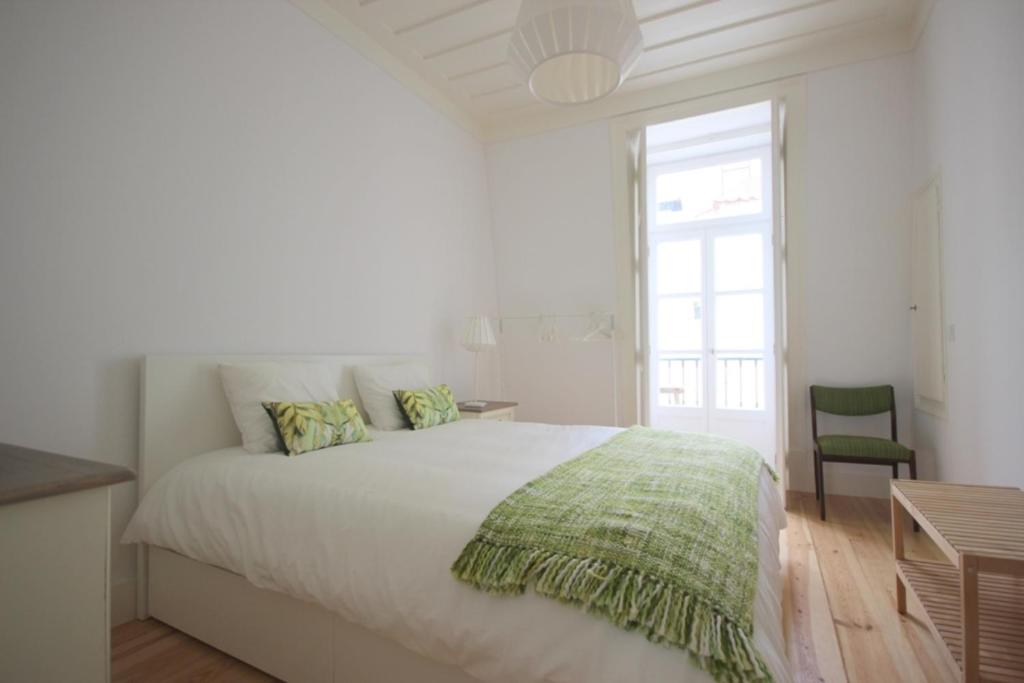 a white bedroom with a large bed and a window at The Lookout Duplex - Bairro Alto in Lisbon