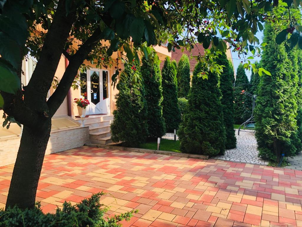 a house with a brick patio and a tree at Pensiunea Perla in Baile Felix